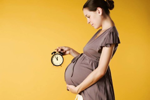 Беременная женщина с часами в руках