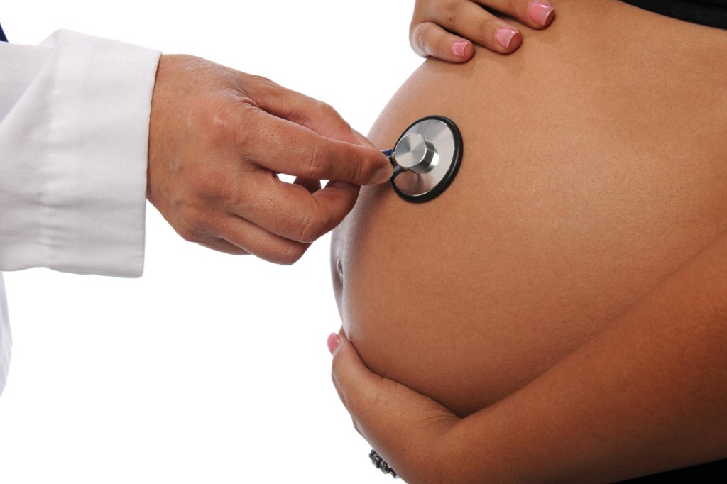 Живот беременной слушают стетоскопом