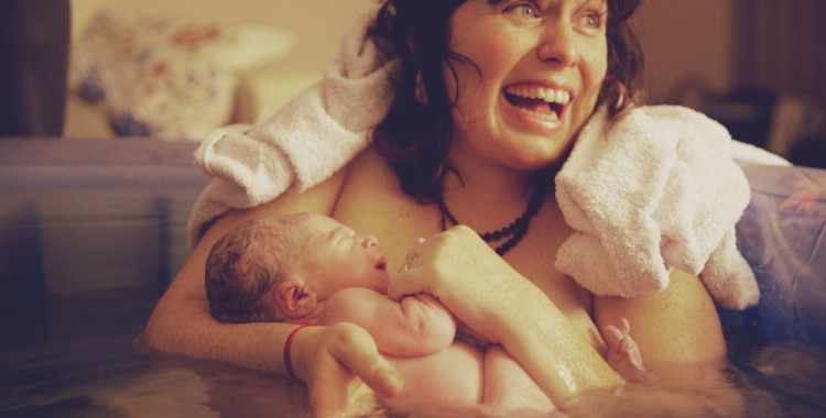 Счастливая только что родившая женщина с ребенком на руках